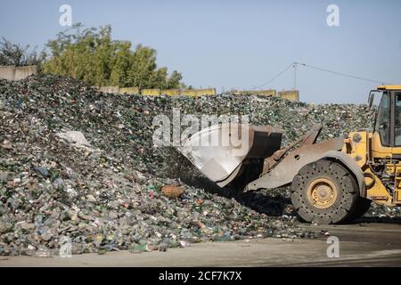 Bukarest, Rumänien - 1. September 2020: Erdbeweger-Betreiber, der einen Stapel leerer Flaschen in einer Glasrecyclinganlage arrangiert. Stockfoto