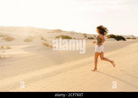 Aktive Frau, die barfuß in der trockenen Wüste läuft Stockfoto