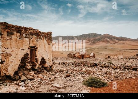 Atemberaubende Landschaft von alten verlassenen Backsteinhäusern in trockener Wüste umgeben von Bergen in Fuerteventura, Las Palmas, Spanien Stockfoto