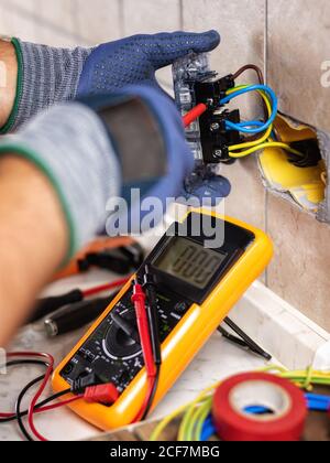 Elektriker bei der Arbeit mit Schraubendreher fixiert das Kabel in den Buchsen eines Wohnelektrik-Systems. Bauindustrie. Stockfoto