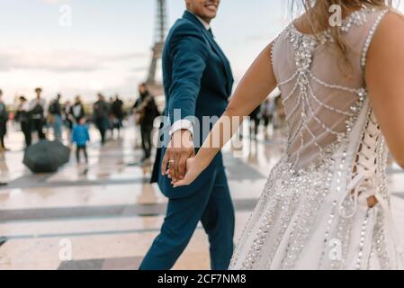 Bräutigam im blauen Anzug und Braut im weißen Hochzeitskleid Langsamer Tanz lächelnd und einander anblickend Eiffelturm im Hintergrund bei Paris Stockfoto