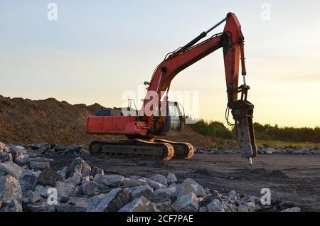 Hydraulikhammer für die Zerstörung von Beton und Hartgestein auf der Baustelle. Bagger auf Sonnenuntergang Hintergrund. Presslufthammer mit Stockfoto