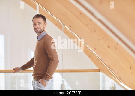 Porträt eines reifen Mannes, der die Kamera anschaut, während er im Stehen steht Das moderne Holzhaus Stockfoto