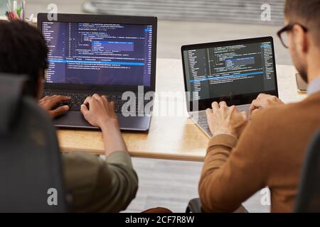 Rückansicht von zwei Grafikern, die am Tisch sitzen Und tippen auf ihren Computern entwickeln sie neue Software Stockfoto