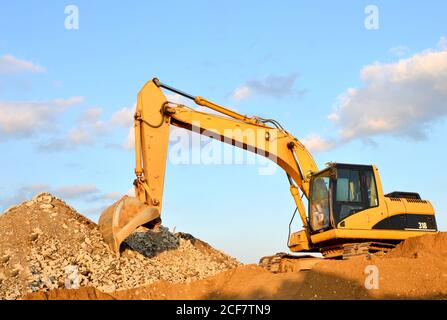 Ein schwerer Bagger in einem Arbeiten bei granitsteinbruch entlädt alte Beton Steine für die Zerkleinerung und Recycling Kies oder Zement. Besondere schwere constructio Stockfoto