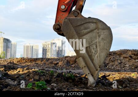 Große Eisenkelle aus Metall. Baggereimer zum Graben einer Grube und eines Rohrleitungsgrabens auf einer Baustelle. Gewerbliche und öffentliche Bauaufträge, tr Stockfoto