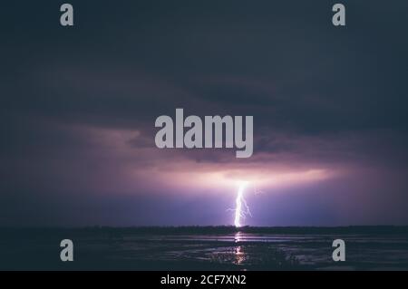 Fantastische Aussicht auf den hellen Blitz, der am dunklen Nachthimmel scheint Über ruhiges Meerwasser in Thailand Stockfoto