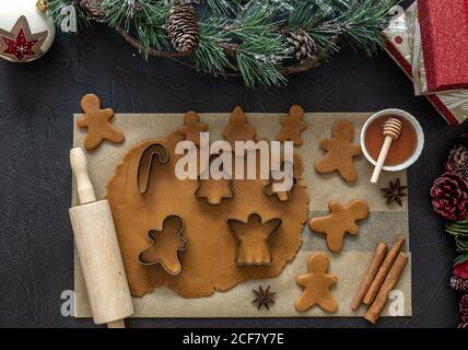 Draufsicht auf ausgerollten Teig für weihnachts-Lebkuchenkekse mit Zubehör auf Pergamentpapier. Stockfoto