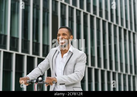 Schwarzer Mann im Anzug auf Elektroroller im Business Center Stockfoto