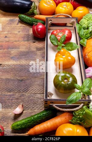 Rahmen von frischem Bauerngemüse in kleiner Box und auf alten rustikalen verwitterten Vintage-Holztisch. Vertikale Ausrichtung. Platz für Text kopieren. Werbung h Stockfoto