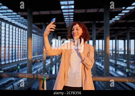 Lächelnde junge Frau beim Selfie am Bahnhof Stockfoto