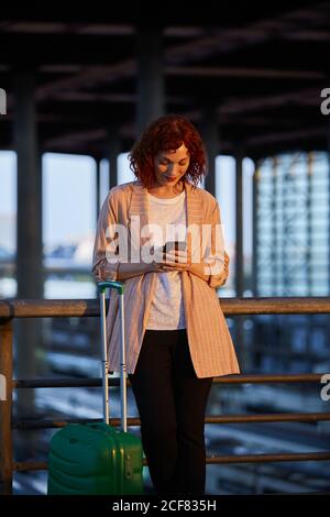 Lächelnde junge Frau, die am Bahnhof telefoniert Stockfoto