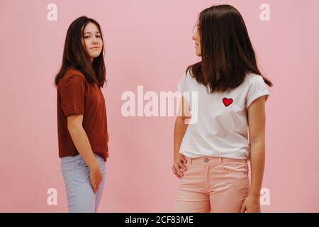 Zwei kleine Zwillingsschwestern lächeln glücklich und blicken in verschiedene Richtungen Stockfoto