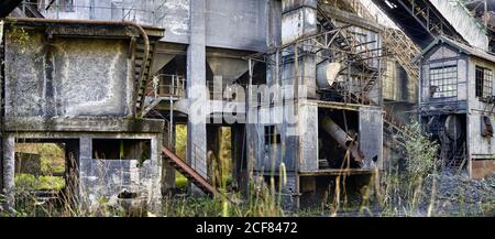 Grauer Beton verfallene Industriegebäude von verlassenen Kohlebergwerk mit Verschiedene Metallleitern und Rohre, die auf Blockaden der Kohle lokalisieren Stockfoto