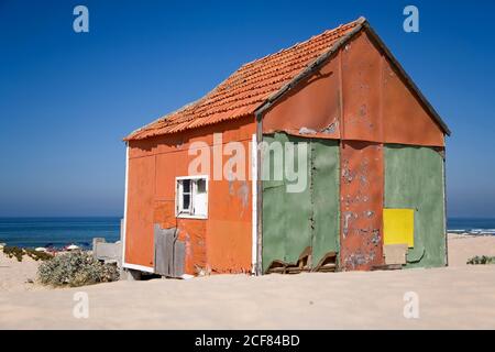 Kleines buntes Haus mit schäbigen Wänden am Sandstrand Mit blauem Himmel im Hintergrund an sonnigen Tagen Stockfoto