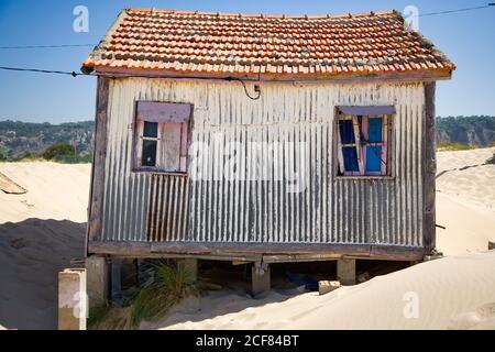 Kleines Haus mit schäbigen Wänden liegt am Sandstrand mit Blauer Himmel im Hintergrund an sonnigen Tagen Stockfoto