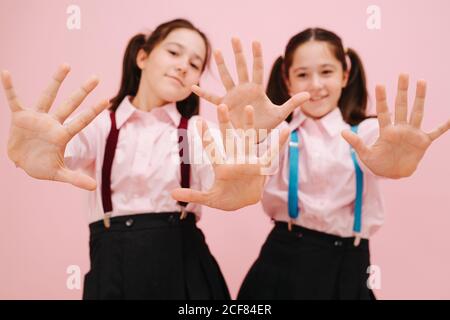 Happy Little Twin Schulmädchen zeigt die Hände auf die Kamera. Verschwommene Gesichter. Stockfoto