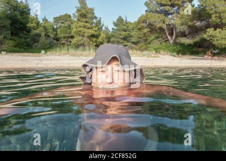 Stirn des schwimmenden Mannes völlig untergetaucht Wasser Blick auf Kamera in sonnigen Tag, Chalkidiki, Griechenland Stockfoto