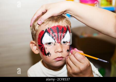 Meister macht Aqua Make-up auf Jungen Gesicht. Halloween-Party. Kinder mit Kindergesicht. Stockfoto