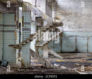 Betonwände und Reste von Treppen in alten verlassenen Industrie Gebäude mit unordentlicher Erde Stockfoto