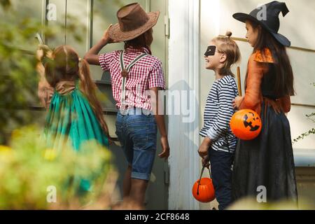 Gruppe von Kindern in Halloween-Kostümen klopft in die Tür Und sagen Sie Trick or Treat Stockfoto