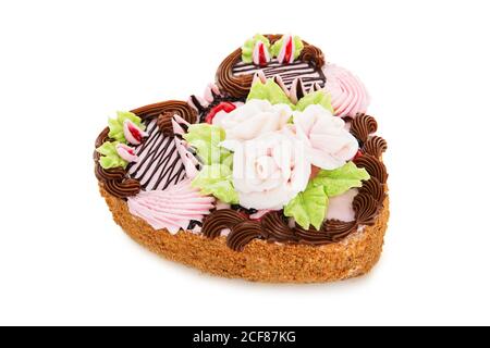 Schokoladenkuchen in Form von Herz mit Sahne verziert Blumen isoliert auf weißem Hintergrund Stockfoto