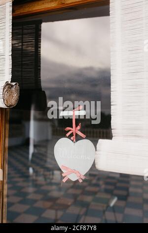 Das Äußere des altmodischen Holzfensters ist mit weißen Vorhängen dekoriert Und Papier Herz an Glas befestigt Stockfoto