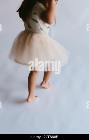 Hohe Winkel Rückansicht von aktiven Kind trägt Tutu Rock tanzen auf weißem Hintergrund, während Spaß im Studio Stockfoto