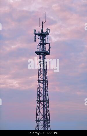 Handy-Turm gegen einen pastellfarbenen Himmel während des Sonnenuntergangs. Stockfoto
