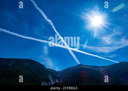 Dampfwege, Contrails in Form eines Kreuzes, in blauem Himmel über den französischen Alpen, Stockfoto