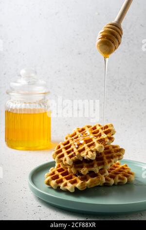 Selektiver Fokus, belgische Zuckerwaffeln mit Blumenhonig auf einem blauen Teller Stockfoto