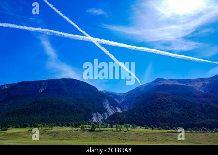 Dampfwege, Contrails in Form eines Kreuzes, in blauem Himmel über den französischen Alpen, Stockfoto