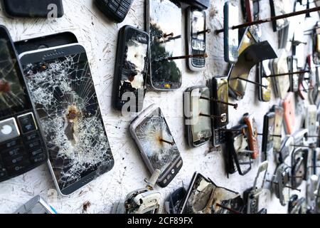 Ein verschwommener Hintergrund von kaputten Telefonen an die Wand genagelt. Stockfoto