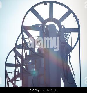 Von unten von Metallrädern und Riemen der Ladearme Von modernen Erdölmaschinen auf dem Hintergrund des blauen Himmels Stockfoto