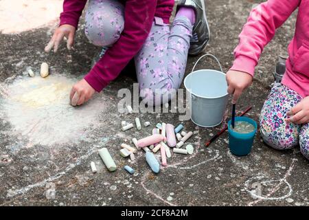 Kinder zeichnen mit Kreide auf den Beton sitzen auf dem Boden. Kunsttherapie, CBT, einfache Kreativitätsübungen. Mädchen Zeichnung mit bunten Kreide Stockfoto