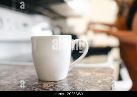 Tasse heißen Latte und Tasse dunklen Kaffee setzen Auf Marmortisch und Ernte anonyme Person, die Tablett mit Frische hausgemachte Cupcakes mit Milchtoping bedeckt Stockfoto