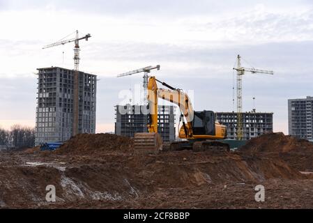 Großer Raupenbagger auf Baustelle im Hintergrund Sonnenuntergang. Bagger graben den Boden für das Fundament, Verlegung Sturm Kanalisation Rohre. Installation Stockfoto