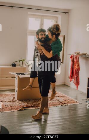 Seitenansicht des liebevollen Paares Huckepack neben Stapel Pappe Boxen zu Hause Stockfoto