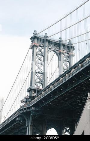 Von unten Brooklyn Brücke mit Metallkabeln und gewölbt Bau auf dem Hintergrund des bewölkten Himmels Stockfoto