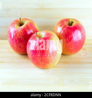 Rote Äpfel auf Holzhintergrund. Drei rote Äpfel auf Holztisch. Stockfoto
