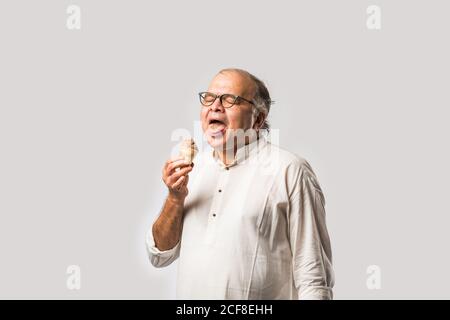 Indischer alter Mann Essen Schokolade Eis in Kegel oder Mango Candy Bar Stockfoto