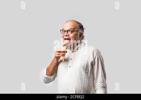 Indischer alter Mann Essen Schokolade Eis in Kegel oder Mango Candy Bar Stockfoto