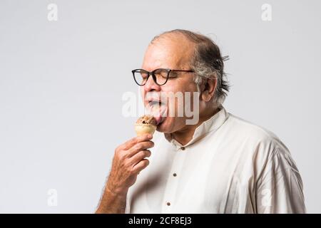 Indischer alter Mann Essen Schokolade Eis in Kegel oder Mango Candy Bar Stockfoto