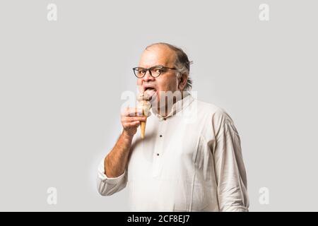 Indischer alter Mann Essen Schokolade Eis in Kegel oder Mango Candy Bar Stockfoto