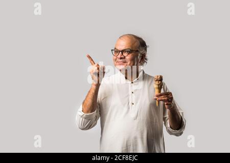 Indischer alter Mann Essen Schokolade Eis in Kegel oder Mango Candy Bar Stockfoto