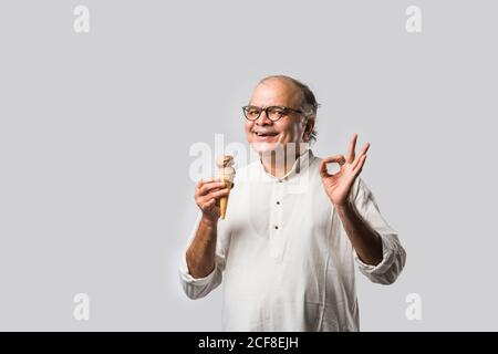 Indischer alter Mann Essen Schokolade Eis in Kegel oder Mango Candy Bar Stockfoto