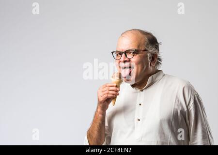 Indischer alter Mann Essen Schokolade Eis in Kegel oder Mango Candy Bar Stockfoto