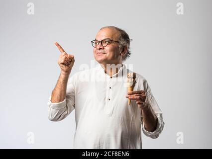 Indischer alter Mann Essen Schokolade Eis in Kegel oder Mango Candy Bar Stockfoto