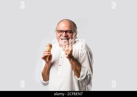Indischer alter Mann Essen Schokolade Eis in Kegel oder Mango Candy Bar Stockfoto