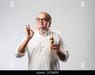 Indischer alter Mann Essen Schokolade Eis in Kegel oder Mango Candy Bar Stockfoto